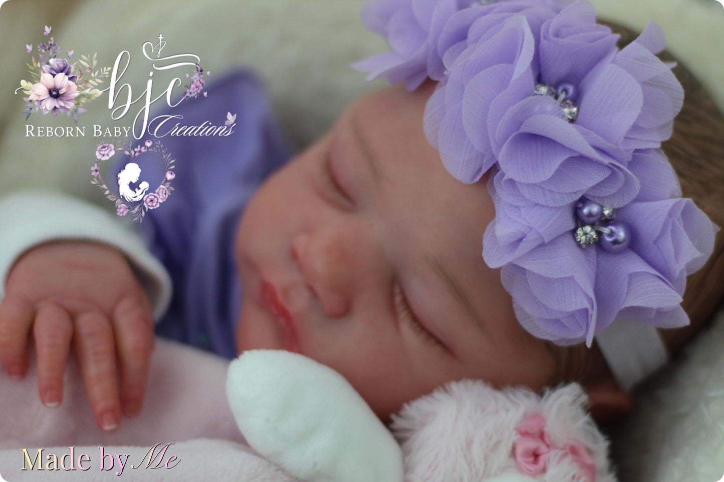 A newborn baby girl is peacefully sleeping, wearing a purple flower headband and a pink stuffed animal. The image is a close-up of the baby's face and features the text "Made by Me" at the bottom.