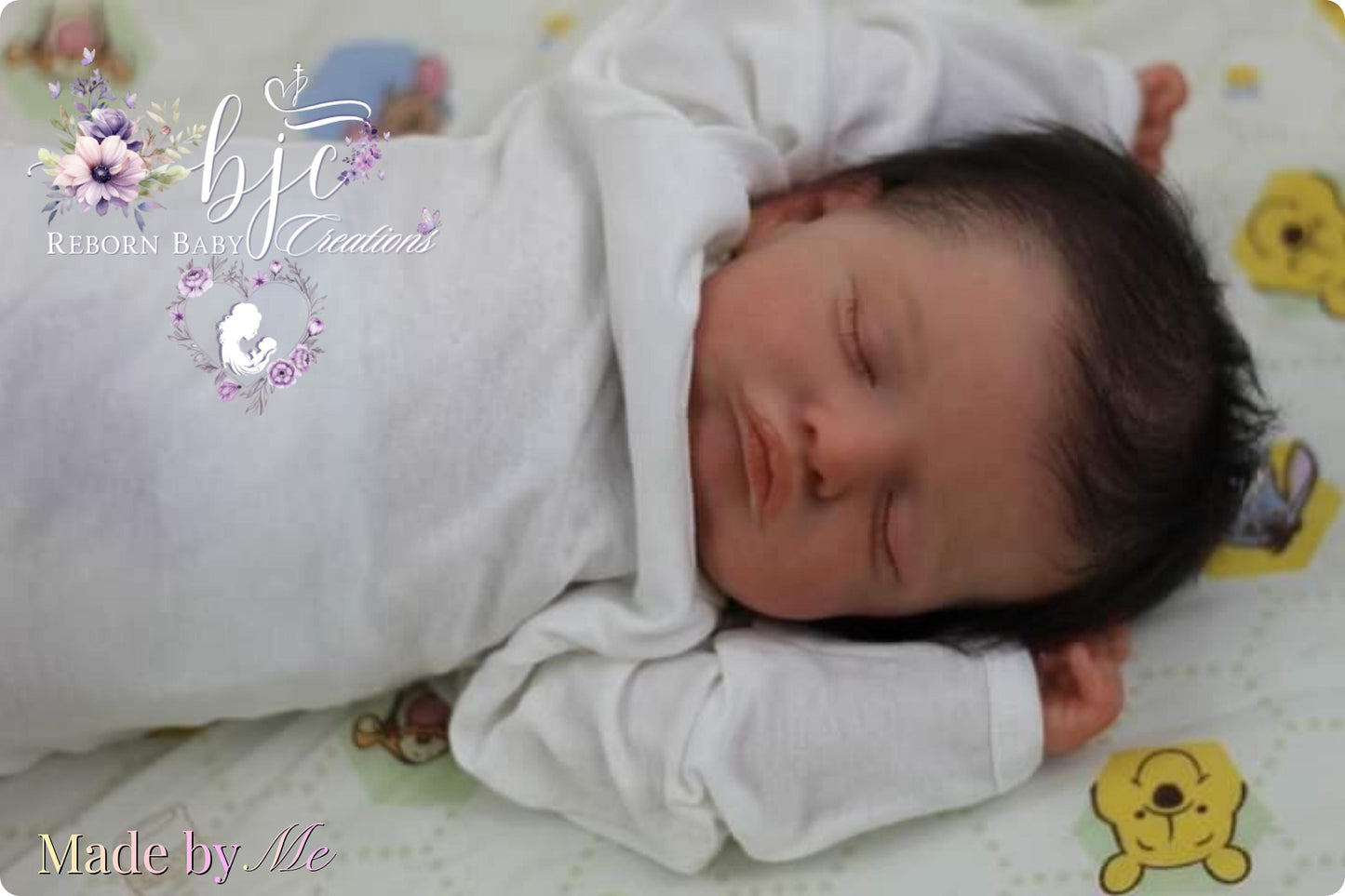 A newborn baby sleeping peacefully on a white blanket with a Winnie the Pooh-themed blanket.