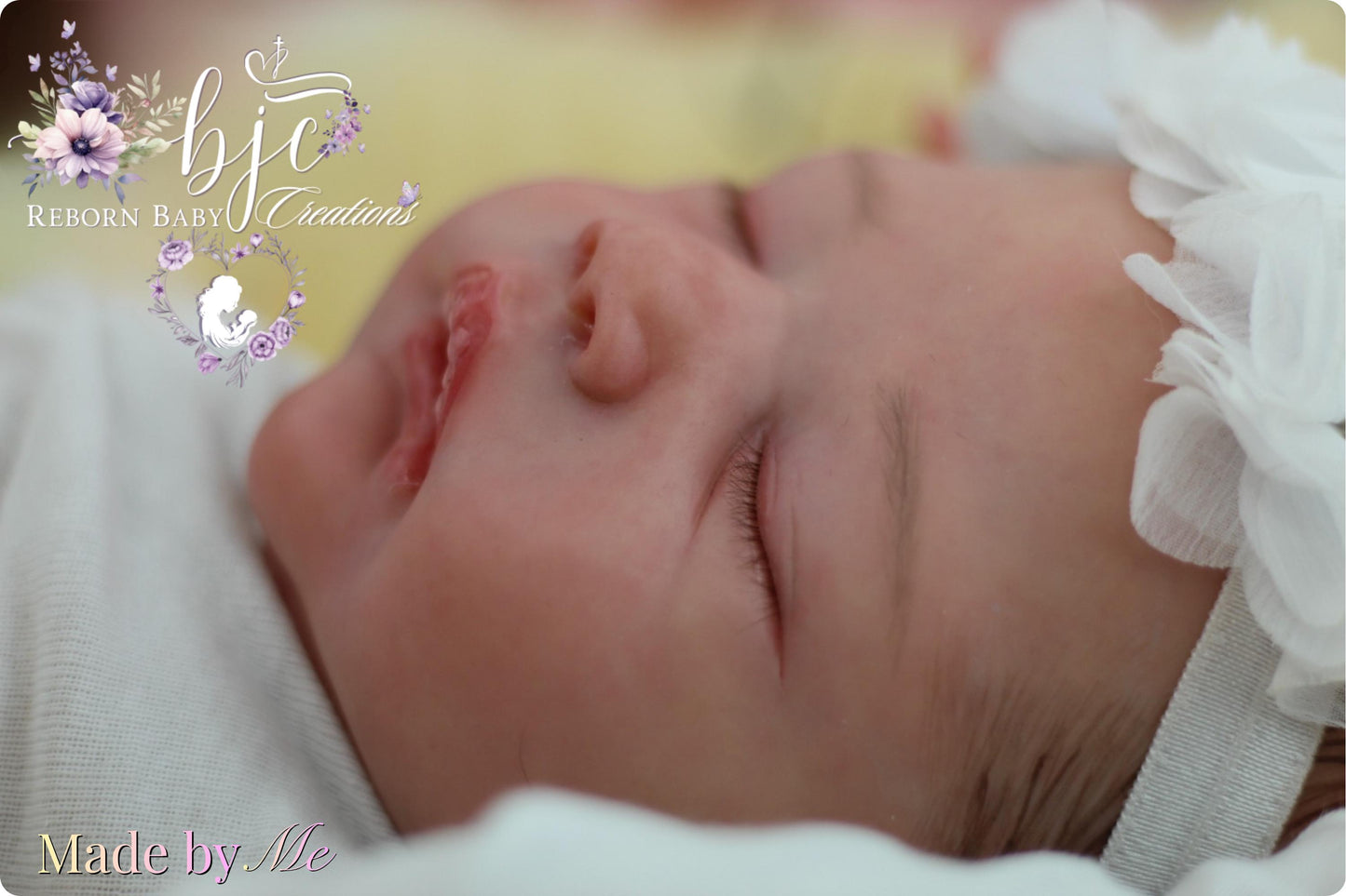 A newborn baby is peacefully sleeping, swaddled in a white blanket and wearing a white flower headband.